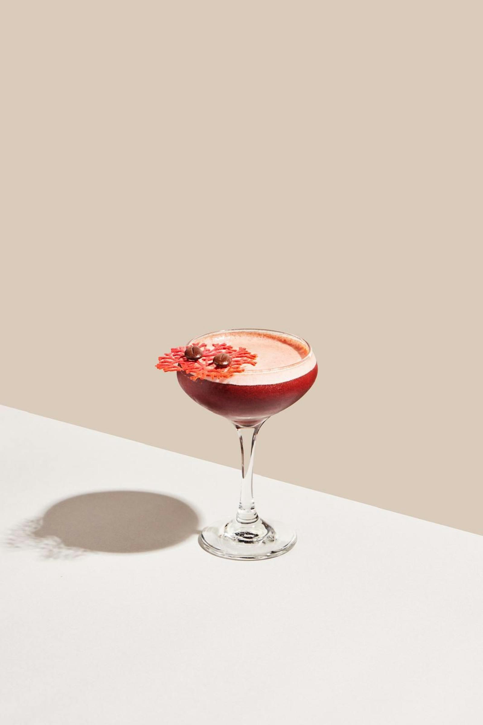 A coffee-foam topped cocktail with coral garnish